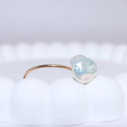 A beautiful baroque pearl gracefully perched on a gleaming gold ring, symbolizing elegance and refined taste.