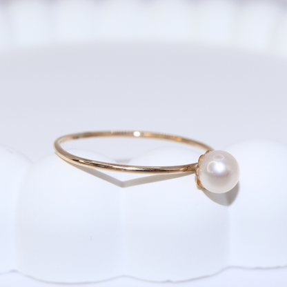 An exquisite gold ring featuring a single, lustrous pearl set on a flower base, embodying sophistication and grace.