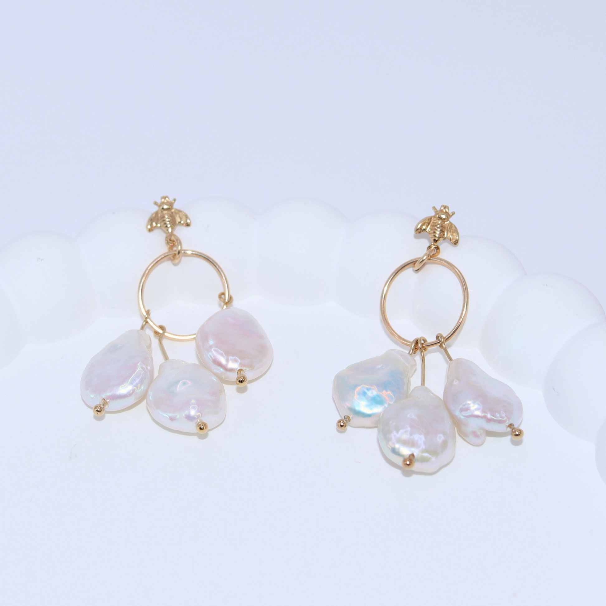 These stunning drop earrings feature a delicate dreamcatcher design, adorned with a bee stud and three luxurious baroque pearls.