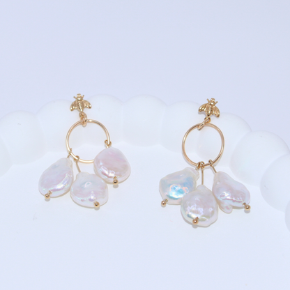 These stunning drop earrings feature a delicate dreamcatcher design, adorned with a bee stud and three luxurious baroque pearls.