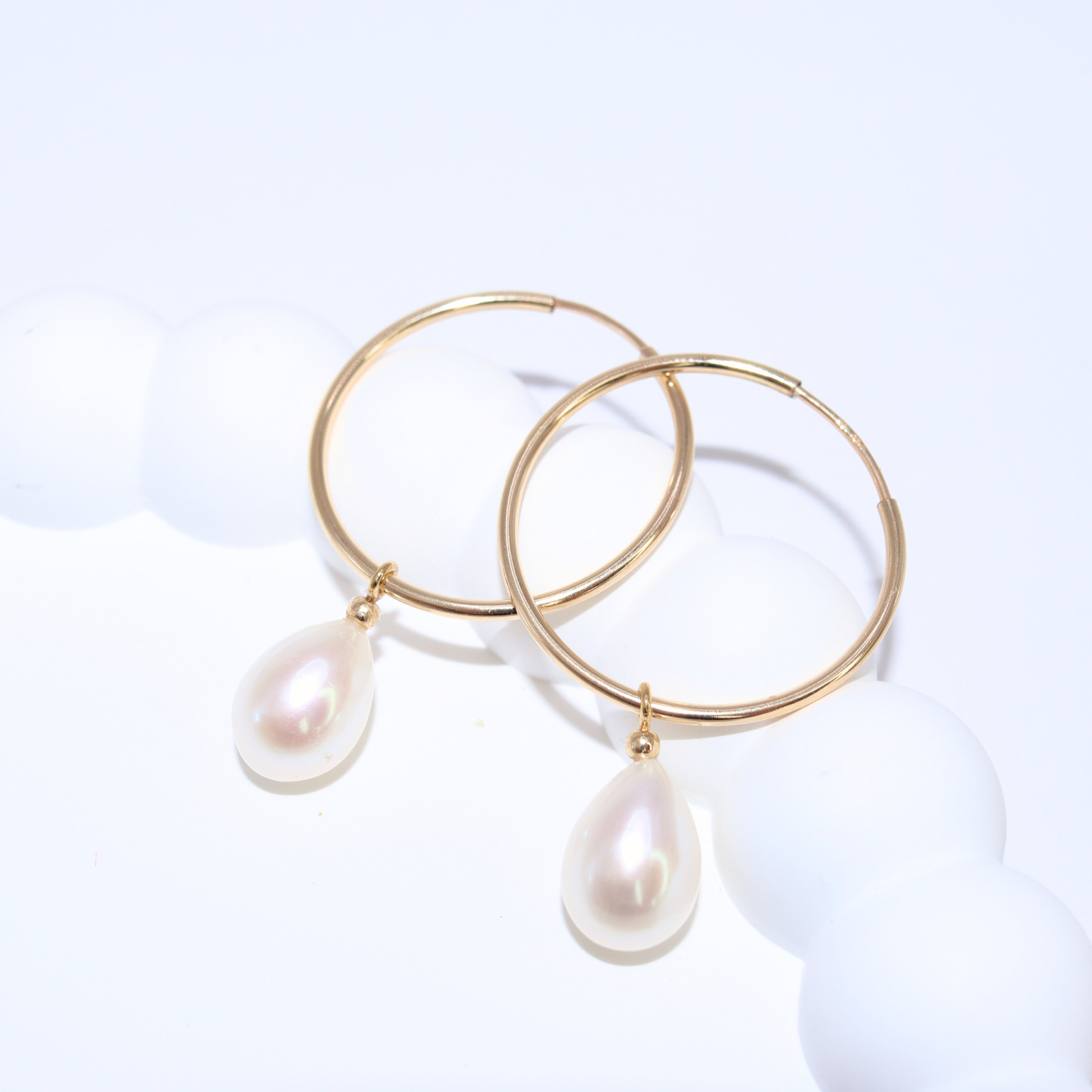  These sophisticated hoop earrings feature a single teardrop pearl, adding a touch of elegance to any outfit. 
