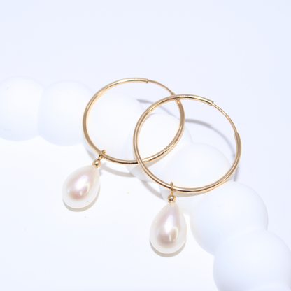  These sophisticated hoop earrings feature a single teardrop pearl, adding a touch of elegance to any outfit. 