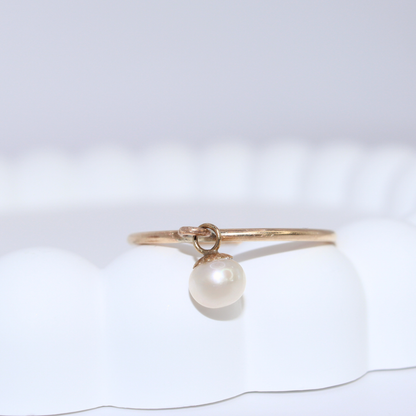 A luxurious gold ring adorned with a single exquisite pearl charm, radiating elegance and timeless beauty.