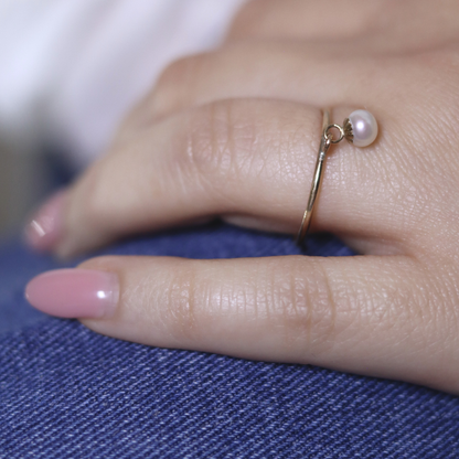 A luxurious gold ring adorned with a single exquisite pearl charm, radiating elegance and timeless beauty.