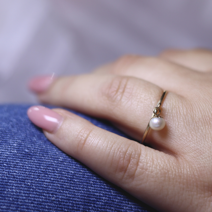 A luxurious gold ring adorned with a single exquisite pearl charm, radiating elegance and timeless beauty.