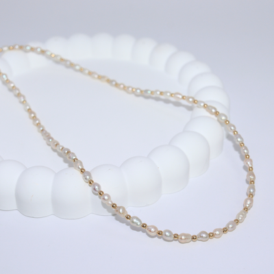 An elegant gold beads and tiny ivory pearls necklace, featuring a harmonious blend of colors and a sophisticated design.