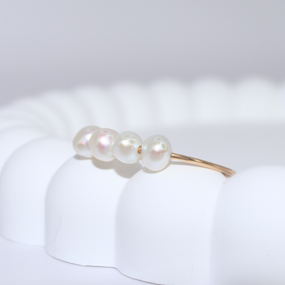 A stunning white pearl ring featuring four exquisite pearls set on a luxurious gold band, radiating elegance and sophistication.