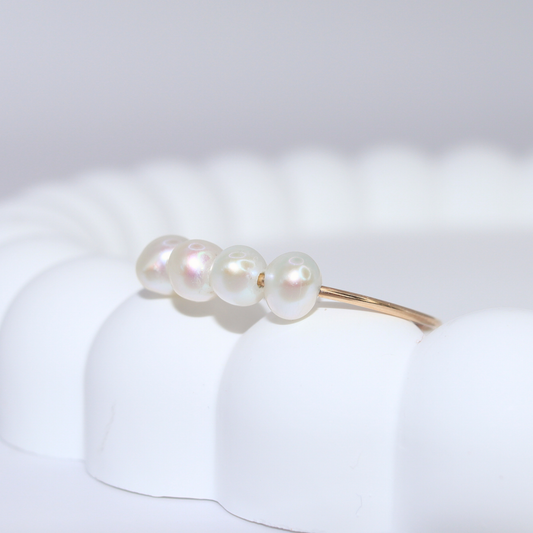A stunning white pearl ring featuring four exquisite pearls set on a luxurious gold band, radiating elegance and sophistication.