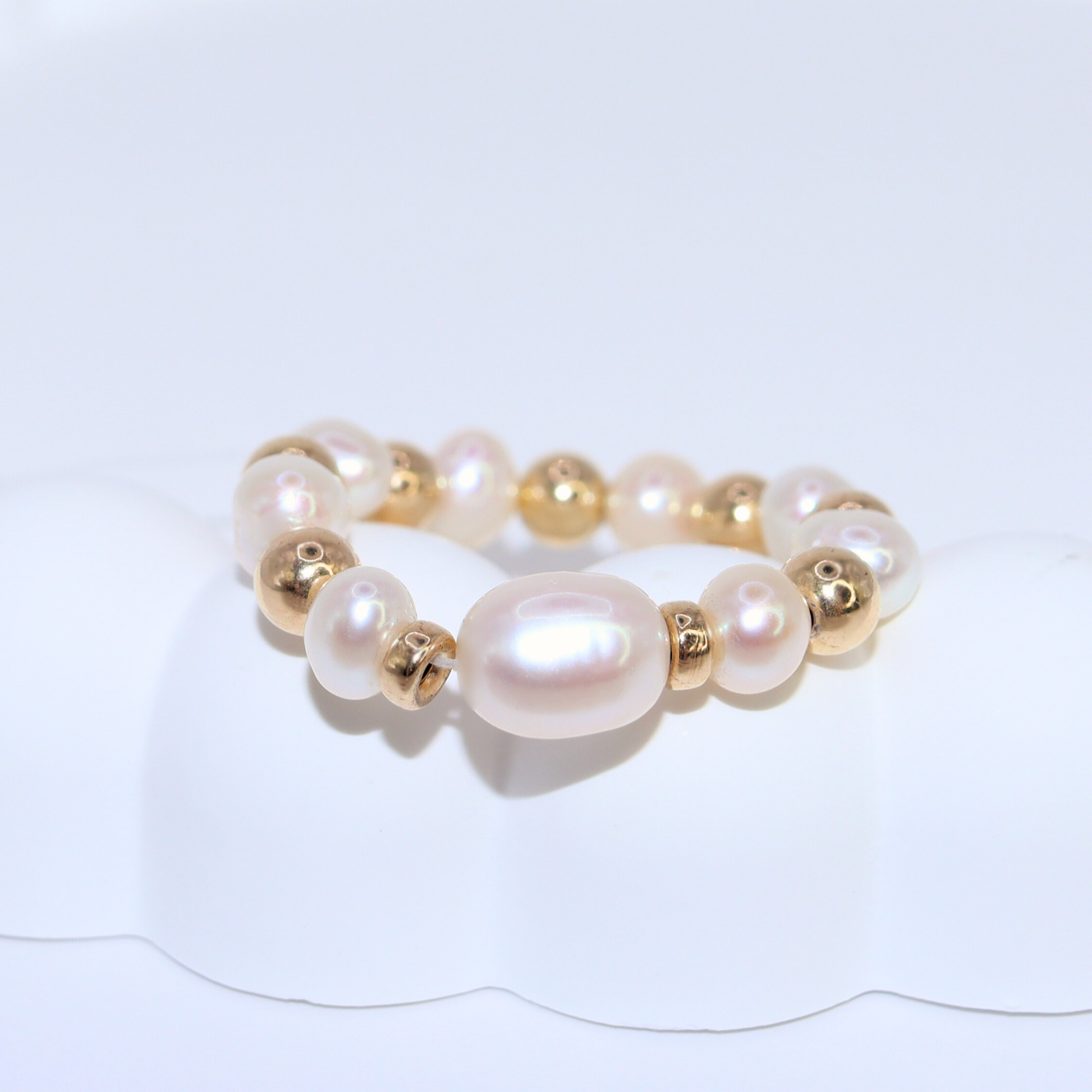 Exquisite gold beads and white pearl ring, a timeless accessory that embodies elegance and refined style.